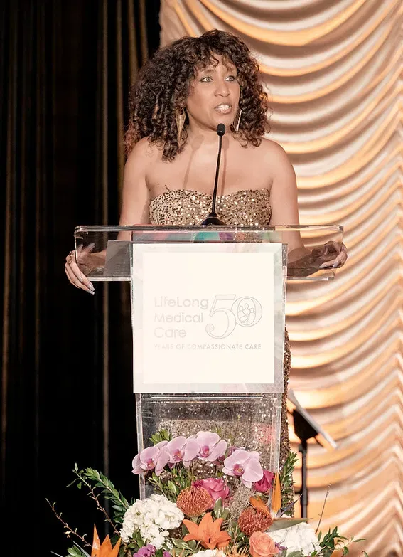 Nikki Thomas speaking from behind a gala podium